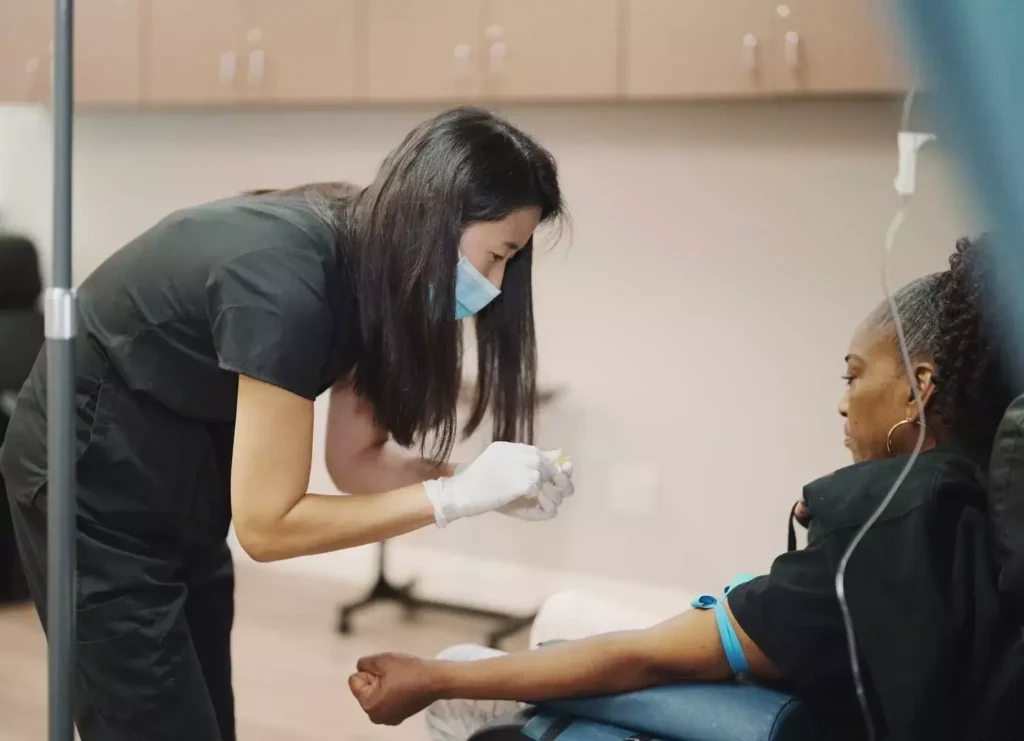 A nurse placing an IV line in a client’s arm at K Wellness