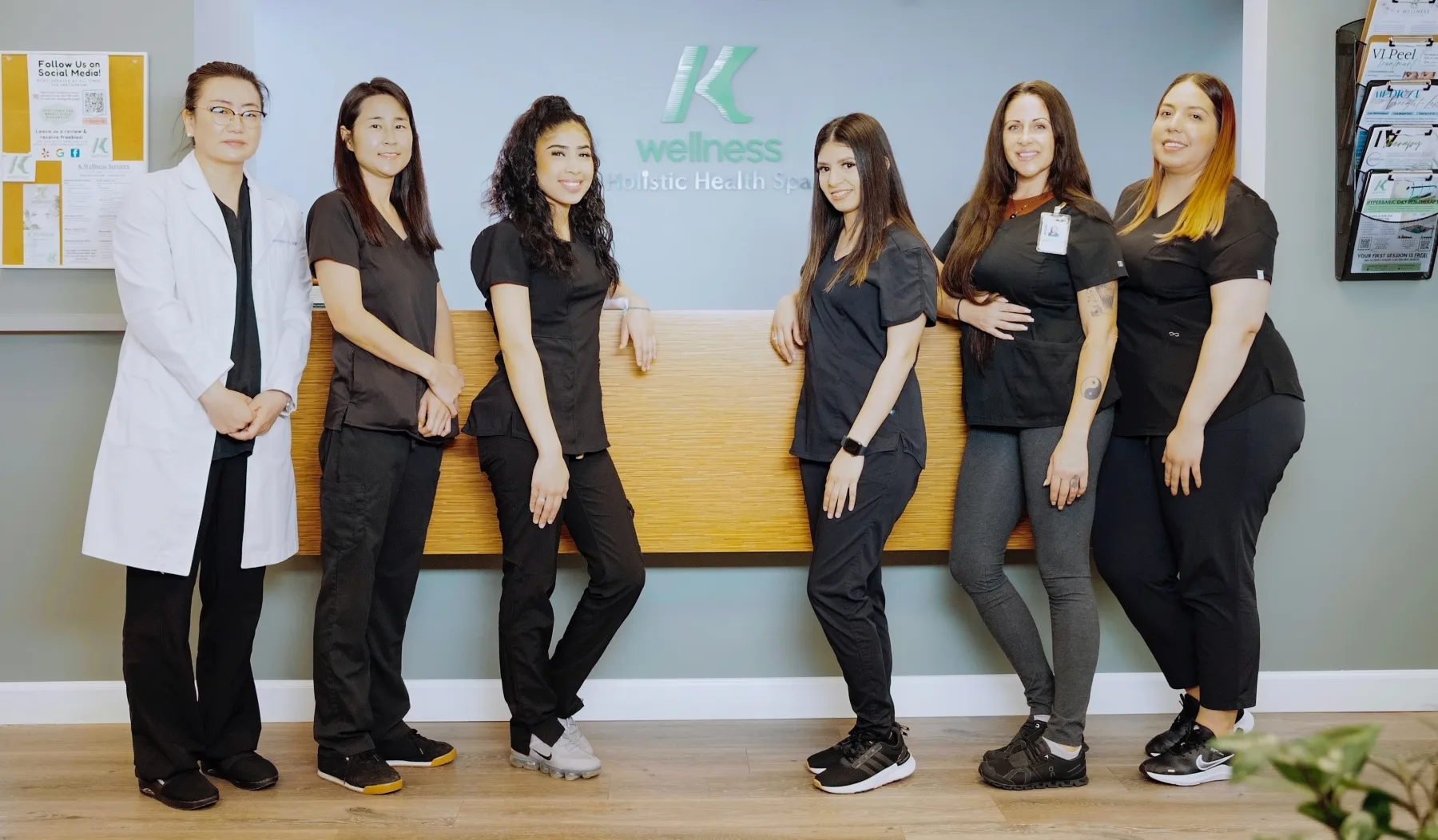 The K Wellness team standing together in front of the reception wall