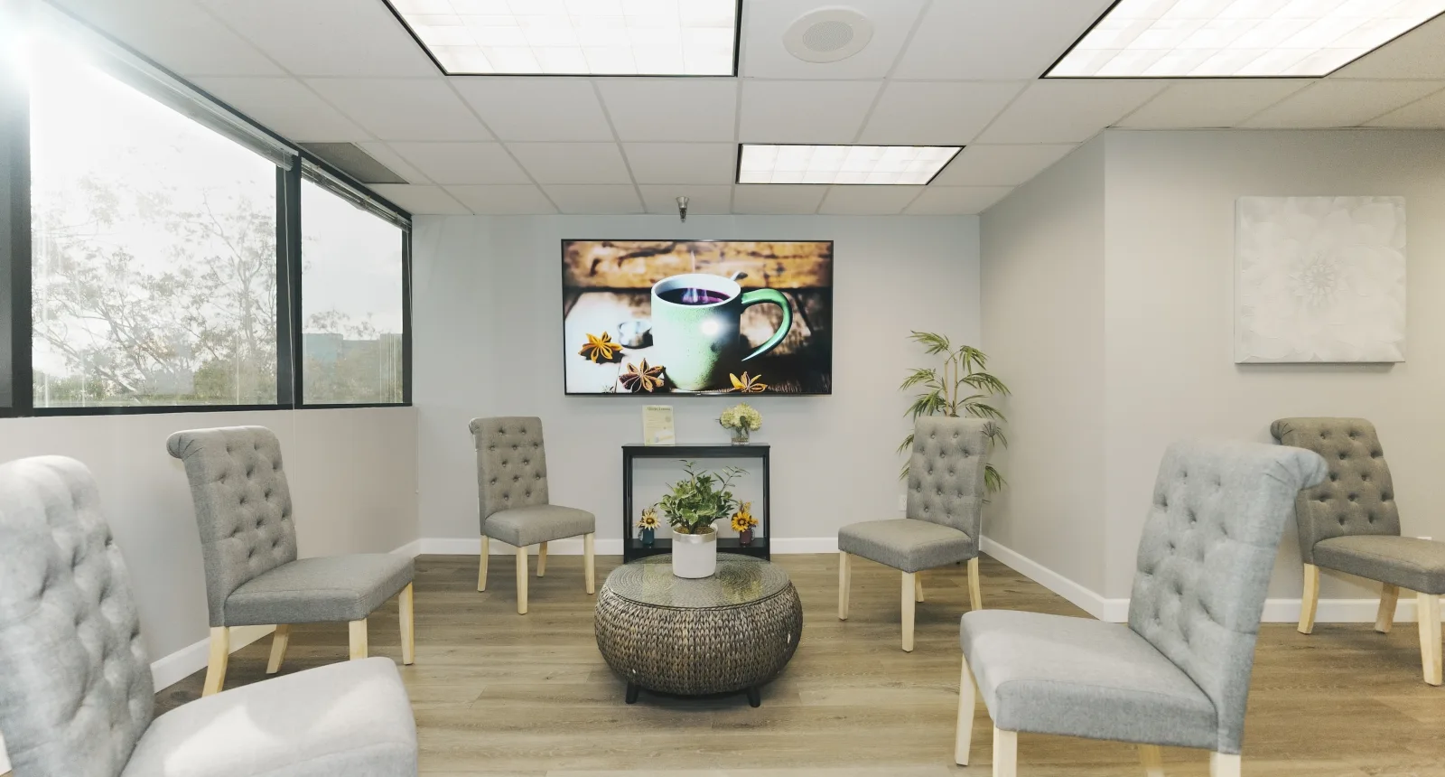 The K Wellness waiting area with armchairs and a wall-mounted screen