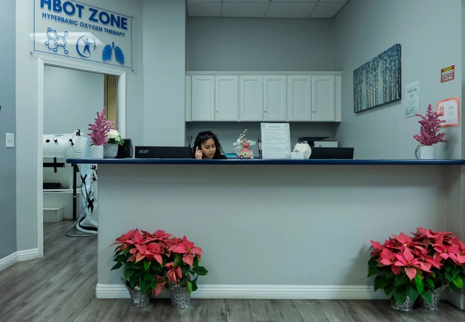 The K Wellness front desk, with the HBOT Zone sign over the doorway to a sit-up hyperbaric chamber