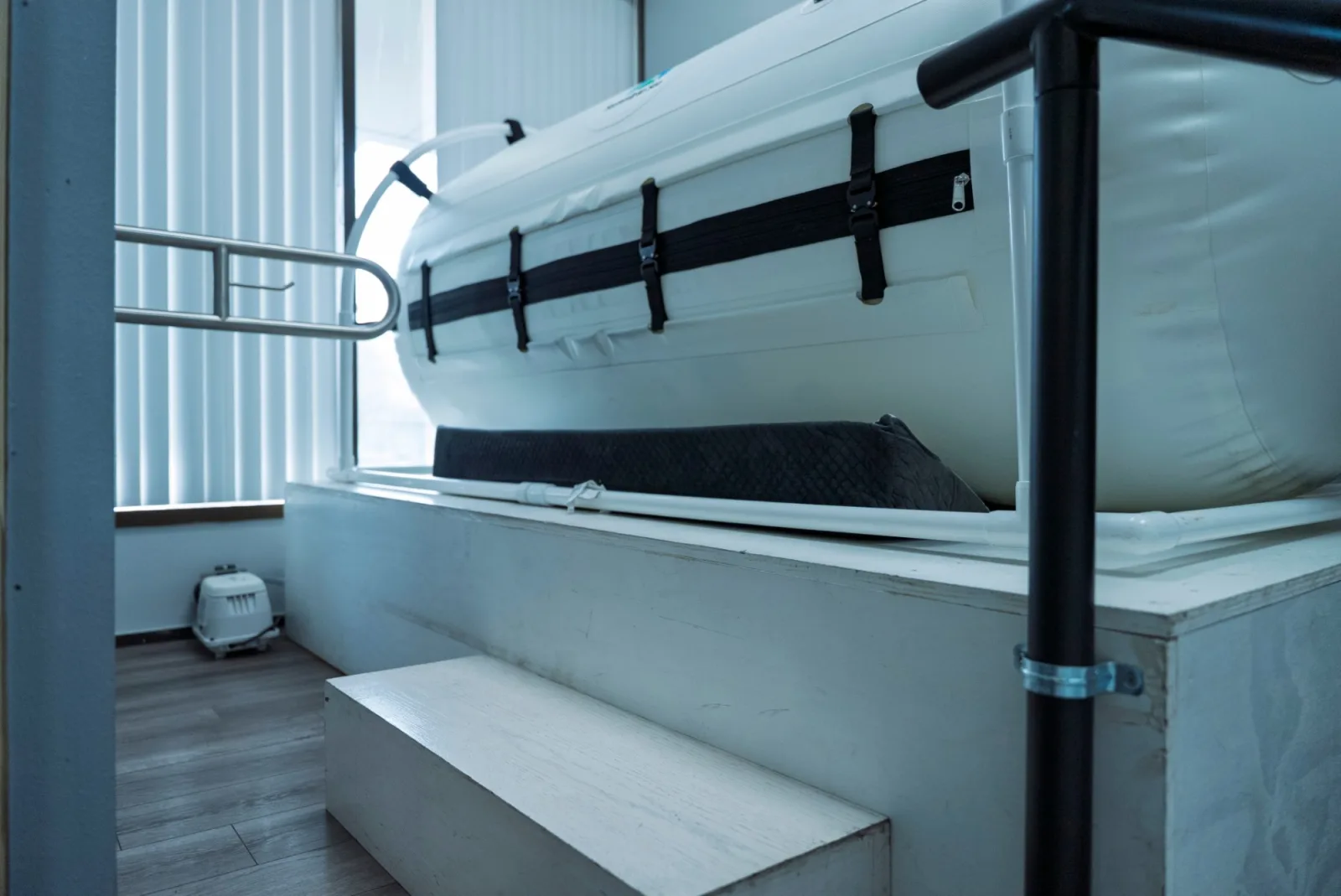 A lie-down hyperbaric chamber at K Wellness, with a step up to the platform and a handrail